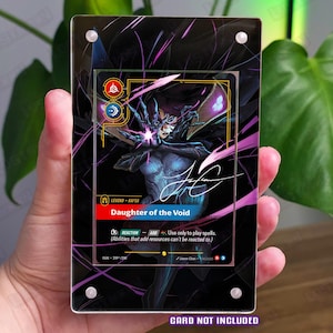 May include: A rectangular acrylic display case for a trading card, featuring a black border with purple abstract streaks. The case has four silver corner screws and displays the text Daughter of the Void, Legend Kai'Sa, and card game details.