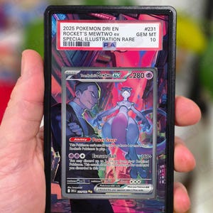 May include: A graded Pokémon card featuring Rocket's Mewtwo ex. The card is encased in a black holder with text indicating it's a Special Illustration Rare, graded GEM MT 10. The card art depicts Mewtwo and a character in a city setting.