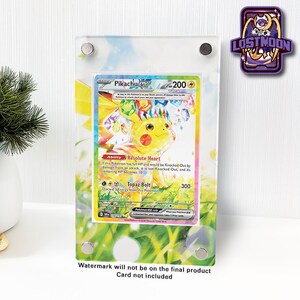 May include: A clear acrylic display frame featuring a Pikachu EX trading card with 200 HP, Resolute Heart ability, and Topaz Bolt attack. The frame has four silver metal standoffs and a colourful, grassy, and floral printed border design.