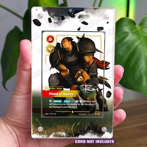 May include: A rectangular clear acrylic display case featuring a printed graphic of a warrior character titled Hand of Noxus. The case has four silver corner screws and includes the text CARD NOT INCLUDED at the bottom in purple lettering.