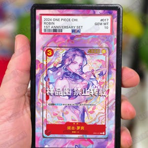 May include: A graded trading card featuring an illustration of a character with purple hair and a sword. The card is from the 2024 One Piece Chi. Robin 1st Anniversary Set, graded GEM MT 10. The card is in a black protective case.