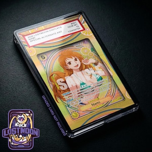 May include: A graded Nami trading card in a clear plastic slab featuring a yellow and orange background with orange slice patterns. The label reads 2026 LOSTMOON DISPLAYS NAMI SPECIAL ALTERNATE ART GEM MT 10. The card displays a character illustration.