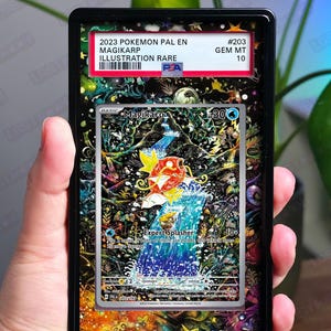 Op de afbeelding: Een beoordeelde Pokémon-kaart met Magikarp, een illustratie zeldzaam uit de 2023 Paldea Evolved-set. De kaart is ingesloten in een zwarte houder met de tekst "CARD NOT INCLUDED". De kaart heeft een kleurrijke illustratie van Magikarp.