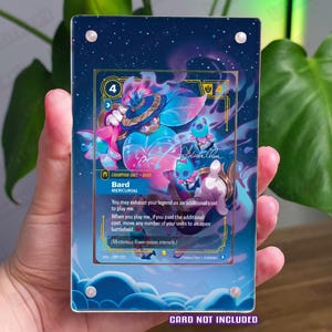 May include: A rectangular acrylic display case with four silver corner screws, featuring a dark blue starry background with cloud motifs at the bottom. The case is designed to hold a trading card, with the text CARD NOT INCLUDED printed at the bottom.