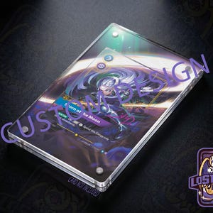 May include: A rectangular clear acrylic display case for a trading card, featuring four silver metal corner screws. The case holds a card with a purple and blue graphic illustration of a character, with the text Scorn of the Moon visible.