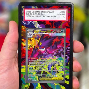 Può includere: Una carta Pokémon Mega Gengar ex in una custodia protettiva. La carta presenta un'illustrazione viola e nera di Mega Gengar. Il testo sulla carta include "Shadowy Concealment" e "Void Gale". La custodia ha uno sfondo rosso e nero con il testo "2026 LOSTMOON DISPLAYS MEGA GENGAR ex SPECIAL ILLUSTRATION RARE".