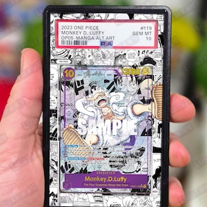 Può includere: Una carta collezionabile valutata con Monkey D. Luffy della serie manga One Piece. La carta è racchiusa in un supporto nero e mostra il testo "2023 ONE PIECE" e "OP05-MANGA ALT.ART". Lo sfondo della carta è un fumetto in bianco e nero.