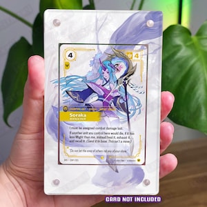 May include: A rectangular clear acrylic display case featuring a swirling purple and white abstract design on the border, secured with four silver corner screws. The case is designed to hold a trading card, with the text CARD NOT INCLUDED printed.