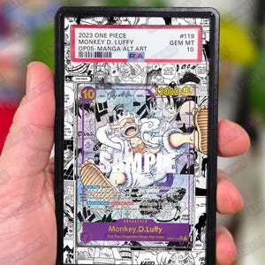 Może przedstawiać: Karta kolekcjonerska One Piece Monkey D. Luffy #119 Manga Alt Art z 2023 roku, oceniona przez PSA i umieszczona w czarnej plastikowej obudowie. Karta posiada czarno-białe tło z paneli mangi oraz centralną ilustrację Luffy'ego w dynamicznej pozie.