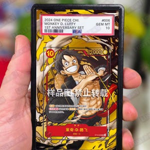 May include: A graded trading card featuring Monkey D. Luffy from the One Piece series. The card has a vibrant yellow and red background with an illustration of the character. The card is encased in a black holder with a label indicating its grade.