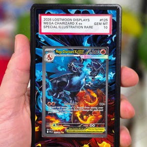 May include: A Mega Charizard X ex trading card in a protective case. The card features a detailed illustration of a blue and orange dragon with the text "Inferno X". The case has a label that reads "2026 LOSTMOON DISPLAYS MEGA CHARIZARD X ex SPECIAL ILLUSTRATION RARE".