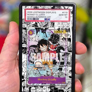 Op de afbeelding: Een verzamelkaart met Monkey D. Luffy uit de mangaserie. De kaart heeft een kleurrijke illustratie van het personage en is ingesloten in een beschermende houder. De kaart is gelabeld met "2026 LOSTMOON DISPLAYS" en "MANGA ALTERNATE ART".