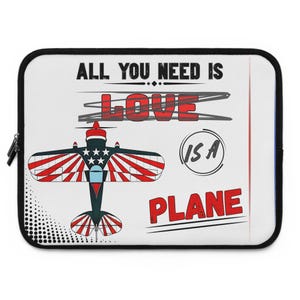 May include: A white laptop sleeve with a black zipper and trim. The design features a red, white, and blue airplane with the text "ALL YOU NEED IS LOVE IS A PLANE."