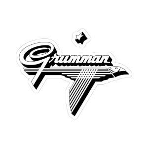 May include: Black and white Grumman logo sticker. The logo features the word "Grumman" in a stylized font, with a graphic of an eagle in flight. A small star is above the logo.
