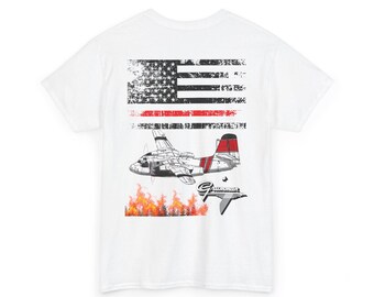 Puede incluir: Camiseta blanca con un diseño desgastado de la bandera estadounidense y una franja roja. Presenta una ilustración de un avión Grumman con detalles rojos, sobre llamas. La palabra "Grumman" está impresa en una fuente estilizada.