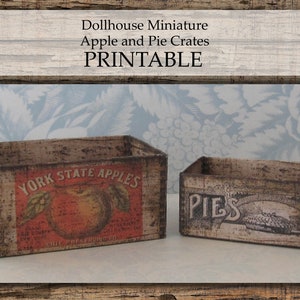 May include: Two miniature wooden crates, one labeled "YORK STATE APPLES" with a red apple illustration and the other labeled "PIES" with a pie illustration.  The crates are printed with a distressed woodgrain pattern.
