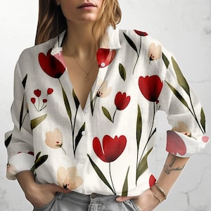 May include: White button-down shirt with a floral pattern of red and peach tulips and green leaves. The long-sleeved shirt has a classic collar and is unbuttoned at the neckline.