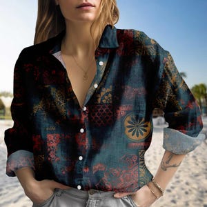 Könnte beinhalten: Ein dunkelblau-grünes Hemd mit rotem Muster. Das langärmlige Hemd hat einen Kragen und weiße Knöpfe. Das Muster umfasst florale und geometrische Formen. Die Ärmel sind hochgekrempelt.