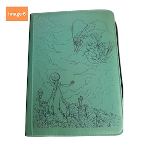 Puede incluir: Una carpeta de color verde menta con cremallera que presenta una ilustraci&oacute;n de l&iacute;neas negras de un Gardevoir en un campo de flores y un Rayquaza volando en el cielo nublado. La cubierta tiene una superficie texturizada y una cremallera oscura.