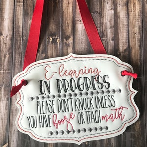 May include: White sign with red ribbon hanging from the top. The sign says "E-learning in progress. Please don't knock unless you have booze or teach math."