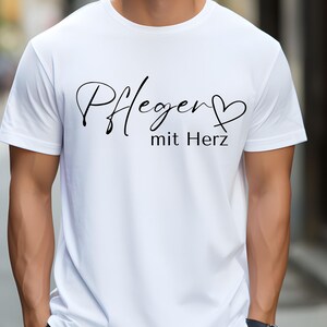 Könnte beinhalten: Weißes T-Shirt mit schwarzem Text, der "Pflegen mit Herz" lautet.