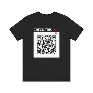 Op de afbeelding: Zwart T-shirt met de tekst "CHECK THIS:" en een zwart-witte QR-code met een rode pijl die ernaar wijst.