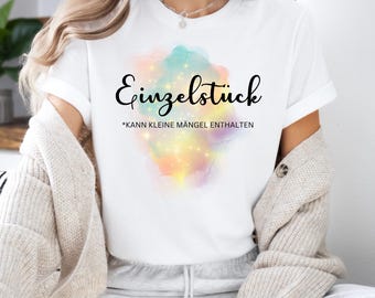 May include: White t-shirt with a colorful watercolor design and the text "Einzelstück *kann kleine Mängel enthalten" in black.
