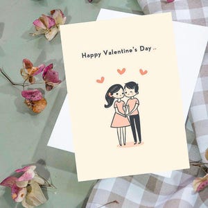 Puede incluir: Tarjeta de felicitación del Día de San Valentín con el texto "Happy Valentine's Day" y una ilustración de una pareja tomados de la mano. La tarjeta es de color beige claro con un sobre blanco y corazones rosas.