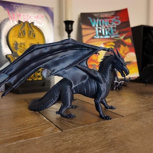 May include: A dark blue dragon figurine with wings outstretched. The dragon has a long tail and is posed in a standing position. The figurine is made of plastic and has a detailed design.