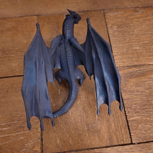 May include: A black dragon figurine with outstretched wings. The dragon has a long tail and a detailed, textured body.