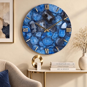 May include: A round wall clock featuring a blue and grey agate stone pattern on the face. The clock has gold-coloured Roman numerals at the twelve, three, six, and nine o'clock positions, with thin gold-coloured hour markers and slender black hands.