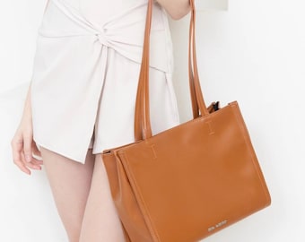 May include: A brown leather tote bag with a single strap and the text "3.1 PHILLIP LIM" printed on the bottom.