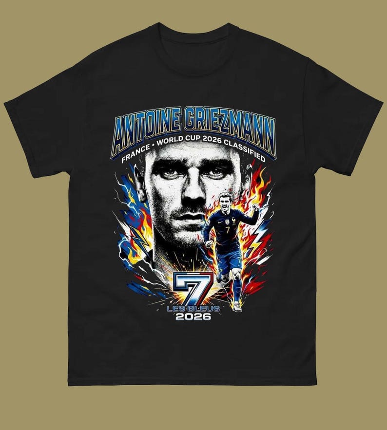 Może przedstawiać: Czarny t-shirt z grafiką Antoine'a Griezmanna, francuskiego piłkarza. Projekt zawiera portret, biegnącą postać oraz tekst "ANTOINE GRIEZMANN FRANCE WORLD CUP 2026 CLASSIFIED" i "7 LES BLEUS 2026".