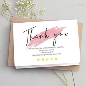 Może przedstawiać: Biała karta z napisem "Thank you" czarnym skryptem na r&oacute;żowym pociągnięciu pędzla. Karta zawiera tekst wyrażający wdzięczność i prośbę o recenzję, z pięcioma złotymi gwiazdkami. Karta jest na brązowej kopercie.