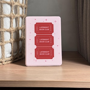 vintage and vibrant Kindle case featuring a soft pink background with three bold red ticket-style designs labeled “LATENIGHT BOOK CLUB” and marked “SINGLE USE.” Decorative pink hearts and sparkles add a whimsical, cozy vibe—perfect for book lovers who enjoy getting lost in stories after dark.