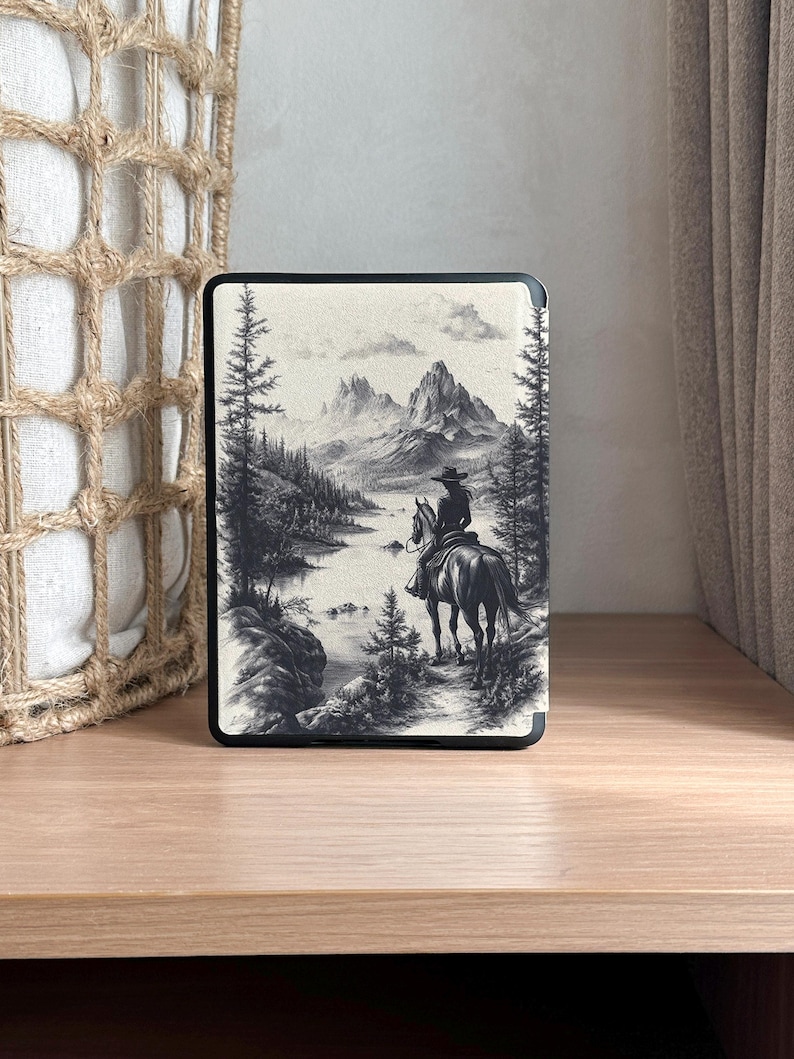 Puede incluir: Una ilustraci&oacute;n en blanco y negro de una persona a caballo cabalgando por un paisaje monta&ntilde;oso. La persona lleva un sombrero de vaquero y el caballo est&aacute; de espaldas al espectador. El fondo es una cordillera con un lago en primer plano.