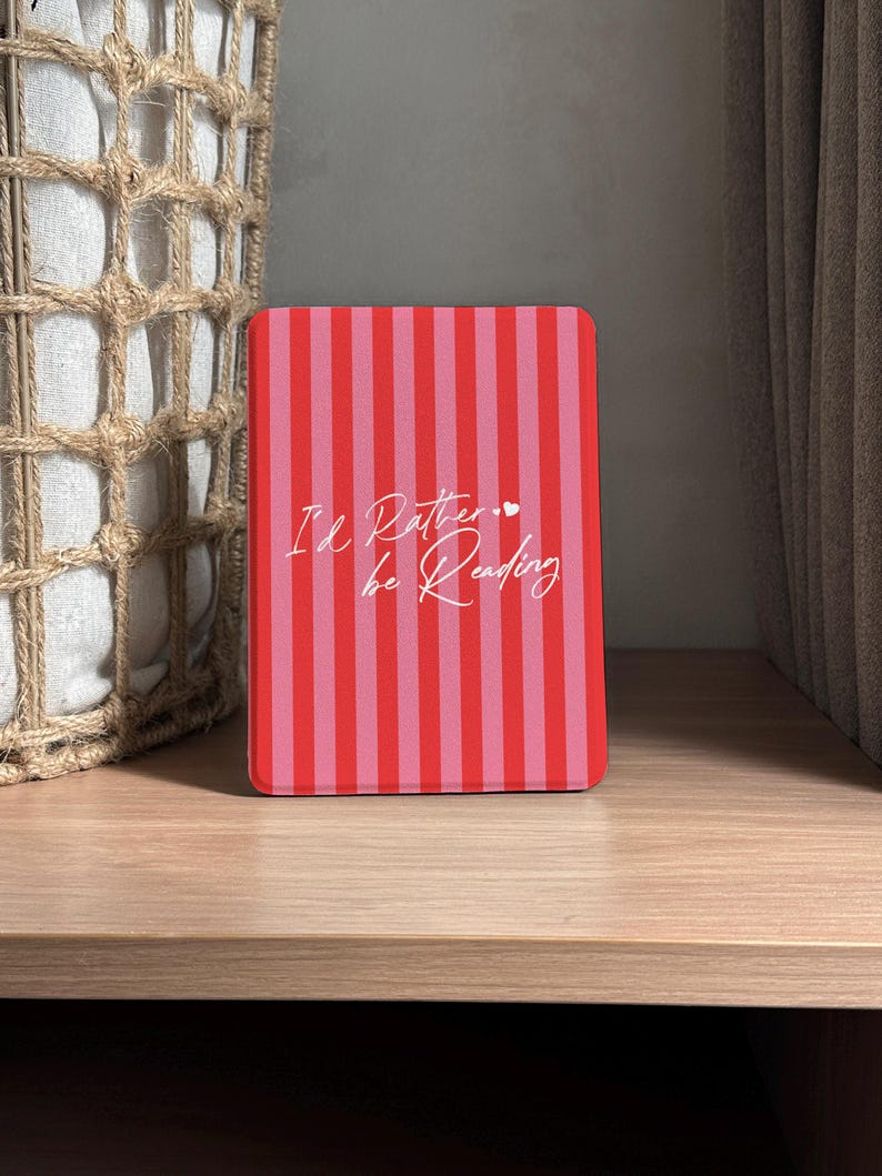 Red and pink striped Kindle case with handwritten-style script that reads “I’d Rather be Reading,” accented by two tiny hearts — a sweet and sassy nod to every book lover’s true priorities. A heartfelt gift for the friend who always sneaks a novel into their bag, your favorite coworker who reads on their lunch break, or anyone who’d rather be curled up with a good story than doing literally anything else. Perfect for Valentine’s Day, Galentine’s Day, or just because they deserve a little joy.