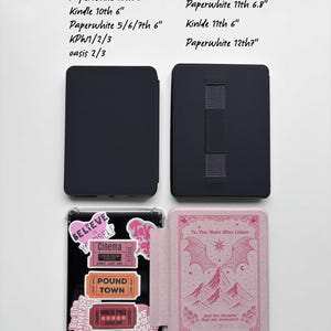 May include: A collection of e-reader cases in black and pink. One case is open, displaying a pink cover with a mountain and bat wing design. The other cases are closed, showing a solid black exterior. Text on the cases includes "Believe in Yourself" and "To The Stars Who Listen."