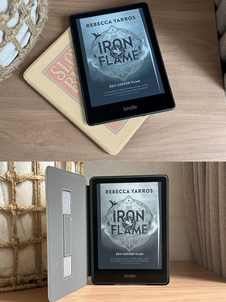 Peut inclure: Une liseuse Kindle noire avec un &eacute;tui gris. L'&eacute;cran affiche la couverture du livre "Iron Flame" de Rebecca Yarros. La couverture du livre pr&eacute;sente un design circulaire avec les mots "Iron Flame" dans une police de caract&egrave;res stylis&eacute;e. Le texte "EEN IJZEREN VLAM" est &eacute;galement visible sur la couverture.