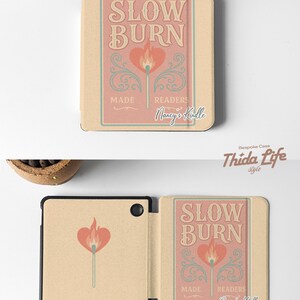 Peut inclure: Une coque Kobo beige et rose avec un graphique d'une allumette avec une flamme en forme de c&oelig;ur. Le texte "SLOW BURN" est au-dessus de l'allumette et "MADE READERS Nancy's Kindle" est en dessous de l'allumette.