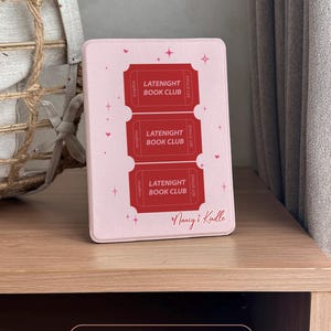 vintage and vibrant Kindle case featuring a soft pink background with three bold red ticket-style designs labeled “LATENIGHT BOOK CLUB” and marked “SINGLE USE.” Decorative pink hearts and sparkles add a whimsical, cozy vibe—perfect for book lovers who enjoy getting lost in stories after dark.