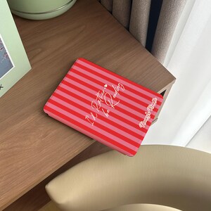 Red and pink striped Kindle case with handwritten-style script that reads “I’d Rather be Reading,” accented by two tiny hearts — a sweet and sassy nod to every book lover’s true priorities. A heartfelt gift for the friend who always sneaks a novel into their bag, your favorite coworker who reads on their lunch break, or anyone who’d rather be curled up with a good story than doing literally anything else. Perfect for Valentine’s Day, Galentine’s Day, or just because they deserve a little joy.
