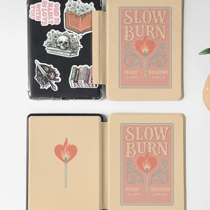 Peut inclure: Une housse pour liseuse double face avec un fond beige et un motif rose repr&eacute;sentant une allumette avec une flamme en forme de c&oelig;ur. Le texte "Slow Burn" est imprim&eacute; sur la housse, ainsi que les mots "Made for Readers".