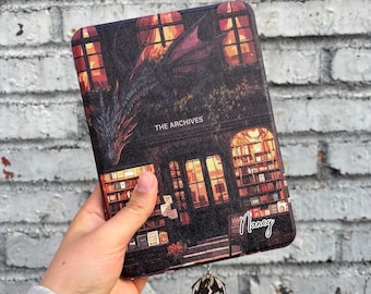 May include: A book cover featuring a black and red dragon design with the text "The Archives" and a name "Nancy" written on the bottom right corner. The cover is made of a textured material and has a silver dragon bookmark.