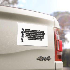 May include: A white rectangular bumper sticker with black text and a silhouette of an alien. The text reads: "Earthlings, you created social media to connect, yet most of you use it to insult strangers and obsess over celebrity drama. Evolution is confused."