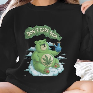 May include: Black sweatshirt with a green cartoon bear holding a bong and a cloud with the text "Don't Care Bear".