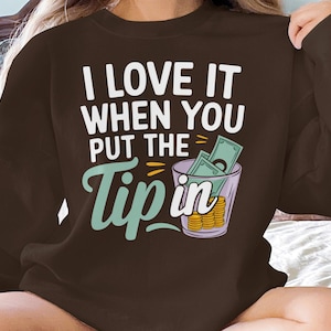 May include: Brown sweatshirt with the text "I love it when you put the tip in" and a cartoon image of a glass with money inside.