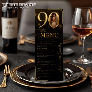 Puede incluir: Una tarjeta de menú negra con detalles dorados para una celebración de 90 cumpleaños. El menú incluye aperitivos, platos principales, postres y bebidas. La tarjeta presenta una foto y el texto "Amelia's 90th Birthday."