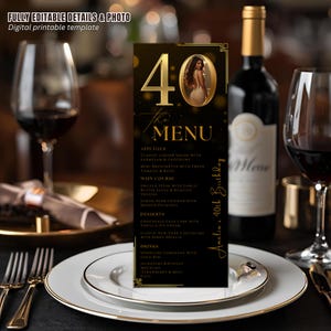 Puede incluir: Una tarjeta de menú negra y dorada para una celebración de 40 cumpleaños. El menú presenta una foto de una mujer y el texto "40 the MENU". La tarjeta está sobre un plato blanco con borde dorado, junto a una copa de vino y una botella de vino.