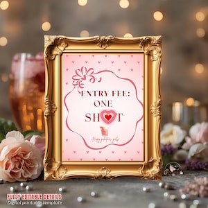 May include: A gold framed sign with the text "ENTRY FEE: ONE SHOT" in a pink heart-shaped design. The sign is on a table with flowers and a drink in the background. The bottom of the sign reads "FULLY EDITABLE DETAILS Digital printable template".